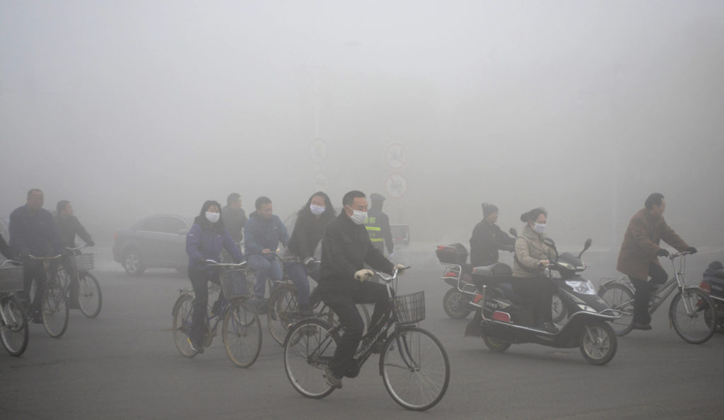 People ride along a street on a smoggy day in Daqing
