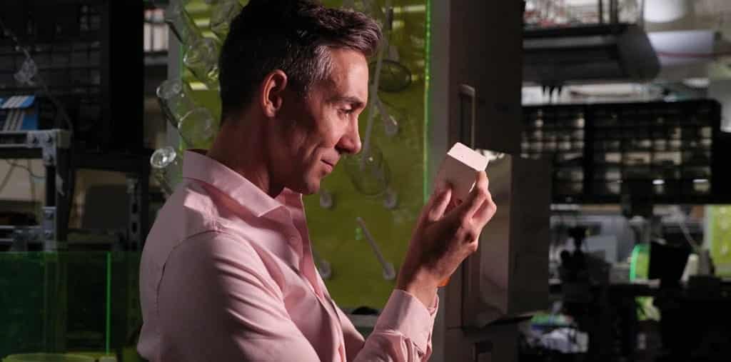 Wil Srubar holds a sample cube of white biogenic limestone produced by calcifying microalgae, known as coccolithophores
