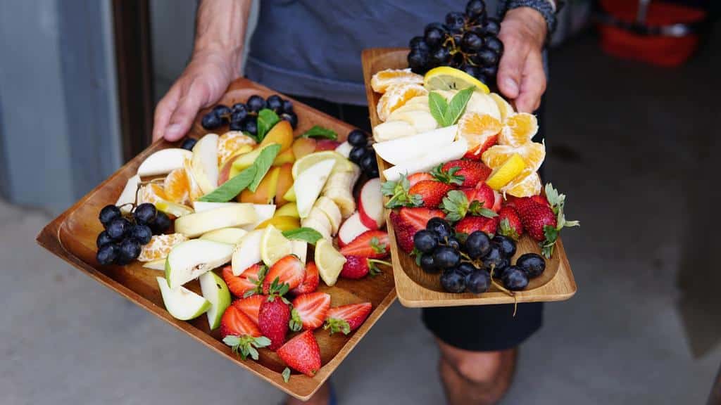 person holding trays of healthy fruits and berries
