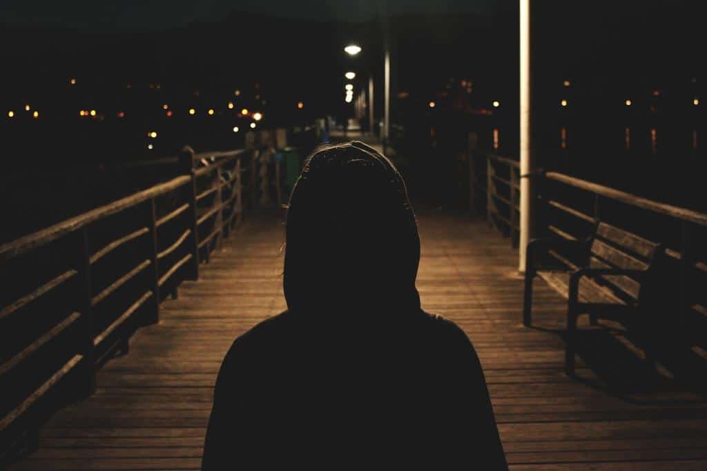 hooded person on pier at night