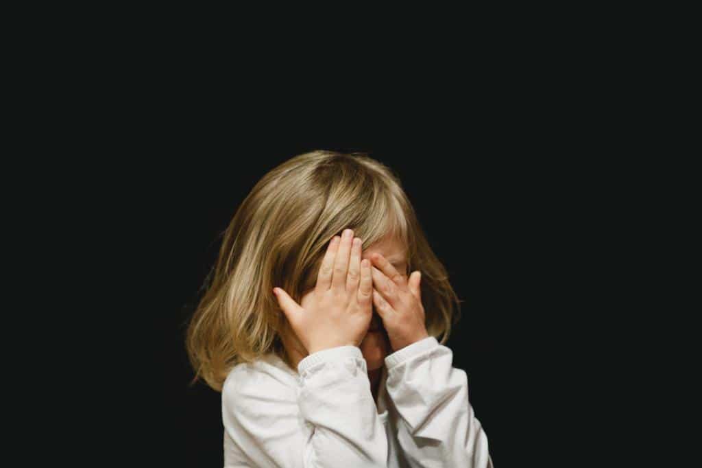 girl hiding face behind hands