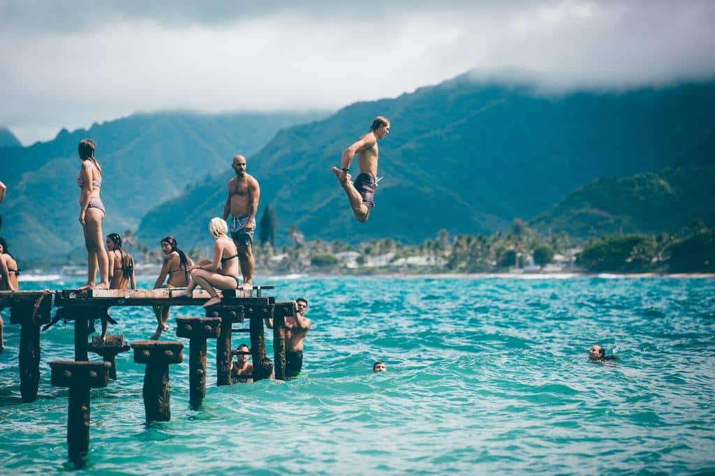 people jumping into water from a dock