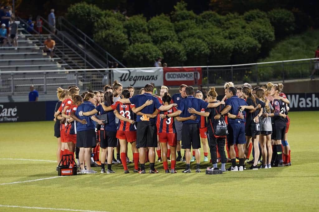 sports team huddled in field