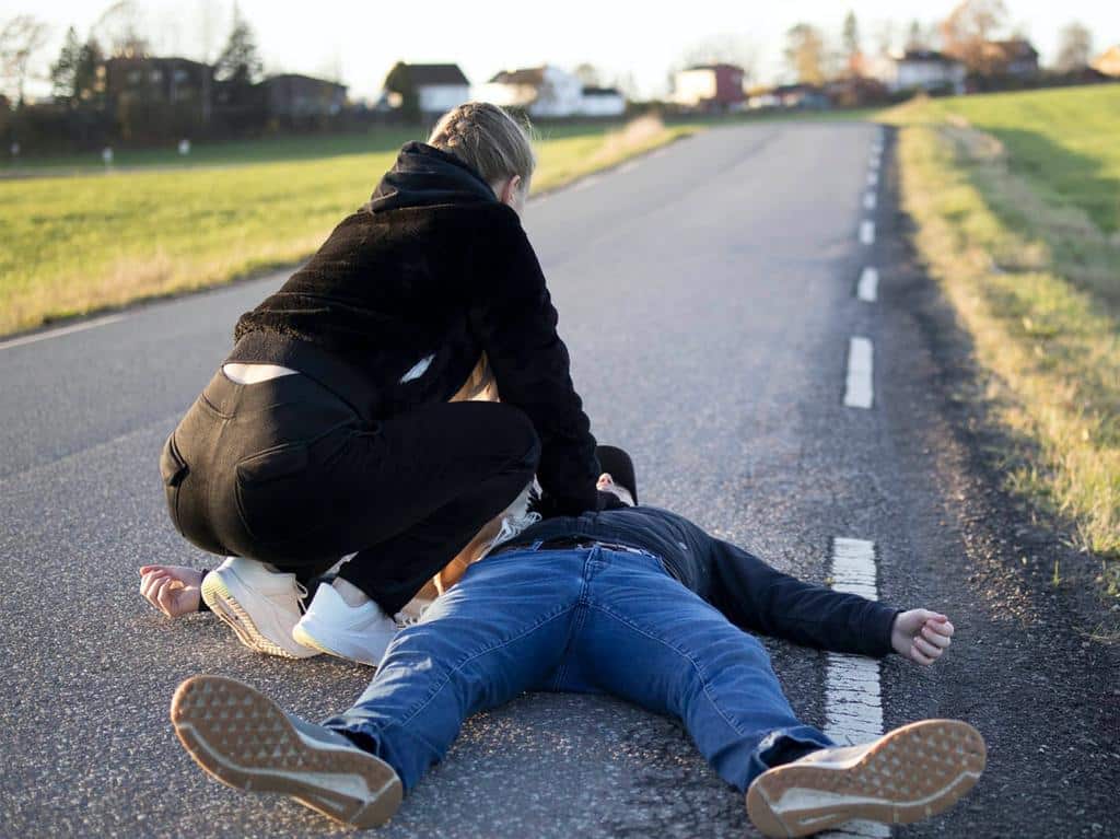 person performing CPR on roadway