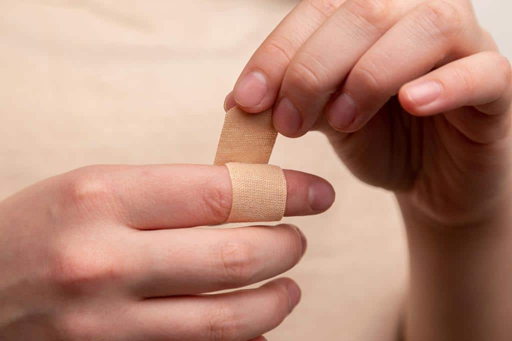 person putting band aid on finger