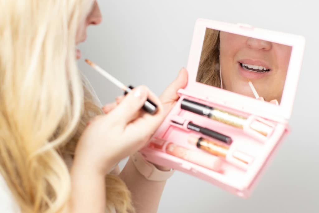 person applying makeup with compact mirror set