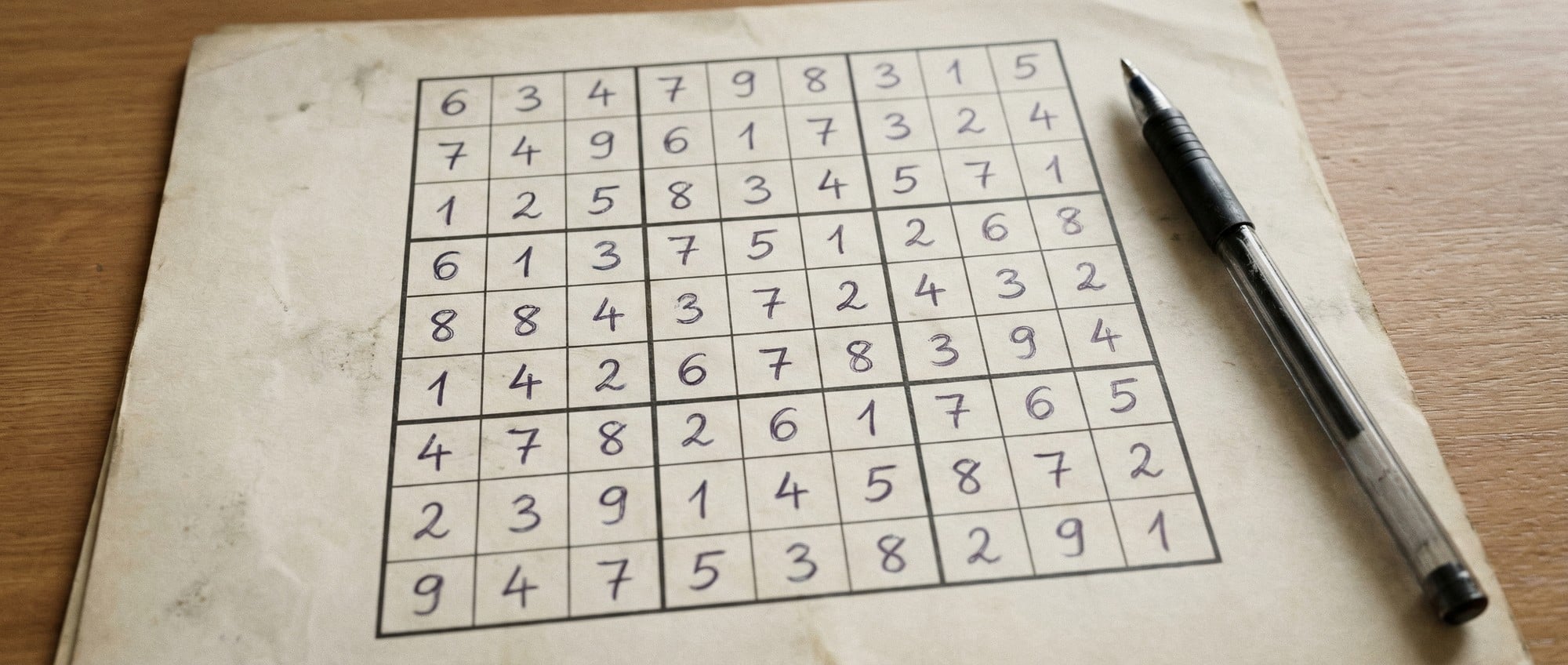 A completed Sudoku puzzle with a pen.