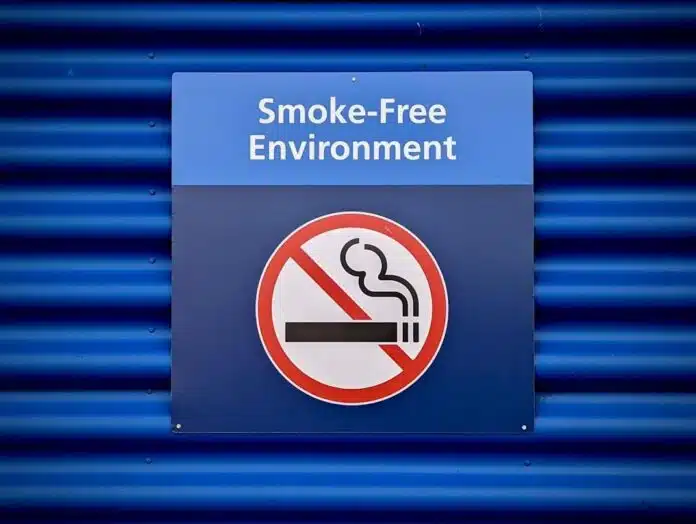 smoke-free-sign A blue sign displaying 'Smoke-Free Environment' above a red circle with a diagonal line through a cigarette, indicating no smoking.