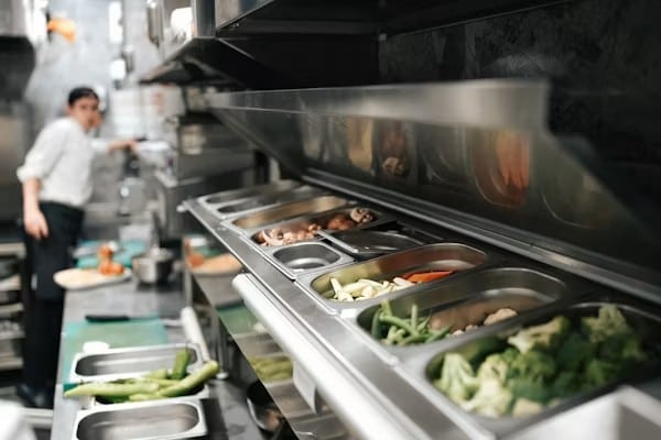 Best Sandwich Prep Table for Restaurants and Cafés in 2026 A stainless steel sandwich prep table with various ingredients like vegetables, mushrooms, and broccoli in metal pans.