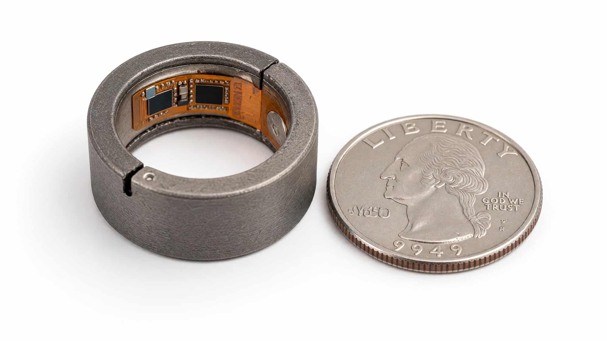The real CHARM smart ring prototype shown next to a US quarter coin for size comparison