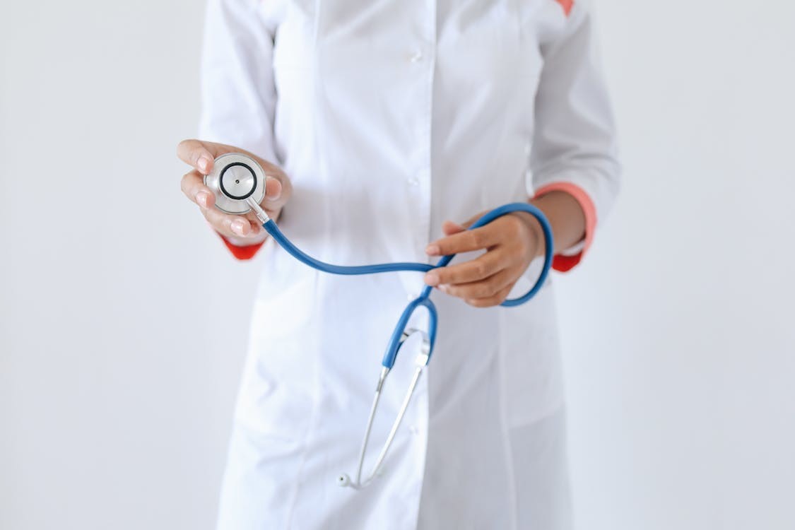 Important Questions to Ask Your Doctor Before Leaving the Hospital A person in a white doctor's coat holds a blue stethoscope with the earpieces towards the camera.