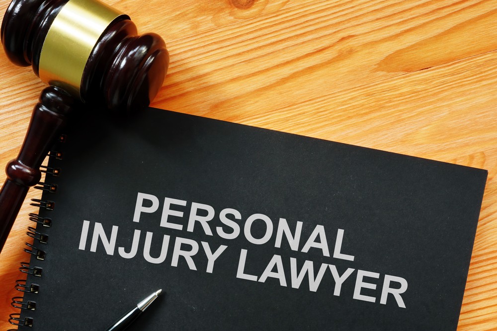 A gavel rests on a black notebook with the words 'Personal Injury Lawyer' in white text.