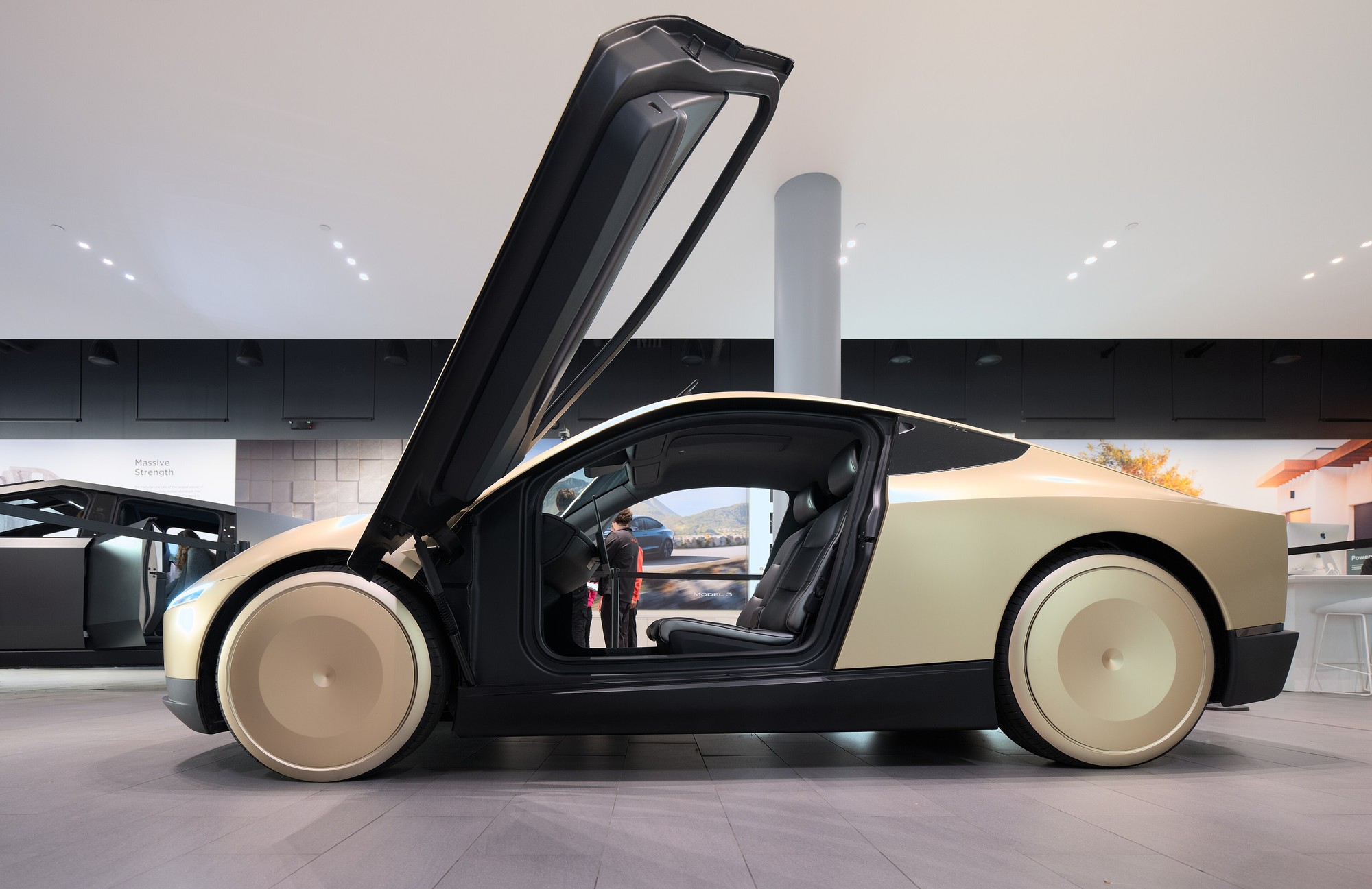 Side view of a white Tesla Cybercab, a two-seat autonomous vehicle with butterfly doors, parked on a street