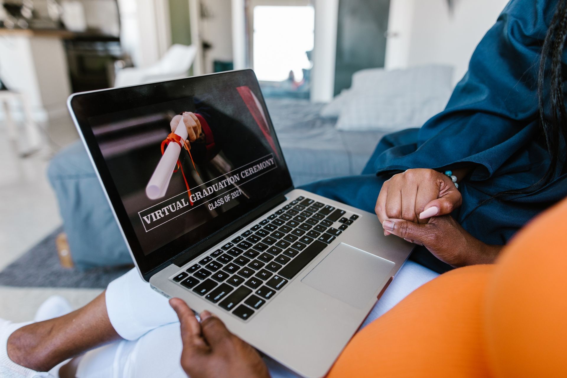 From Educator to Leader: Advance Your Career Without Leaving the Classroom Behind A person is holding a laptop with a virtual graduation ceremony for the class of 2021 displayed on the screen. A diploma is visible on the screen.