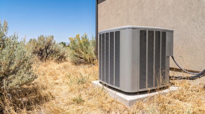 ac-condenser-unit-home Outdoor air conditioning condenser unit beside a suburban home in a dry, sunny climate