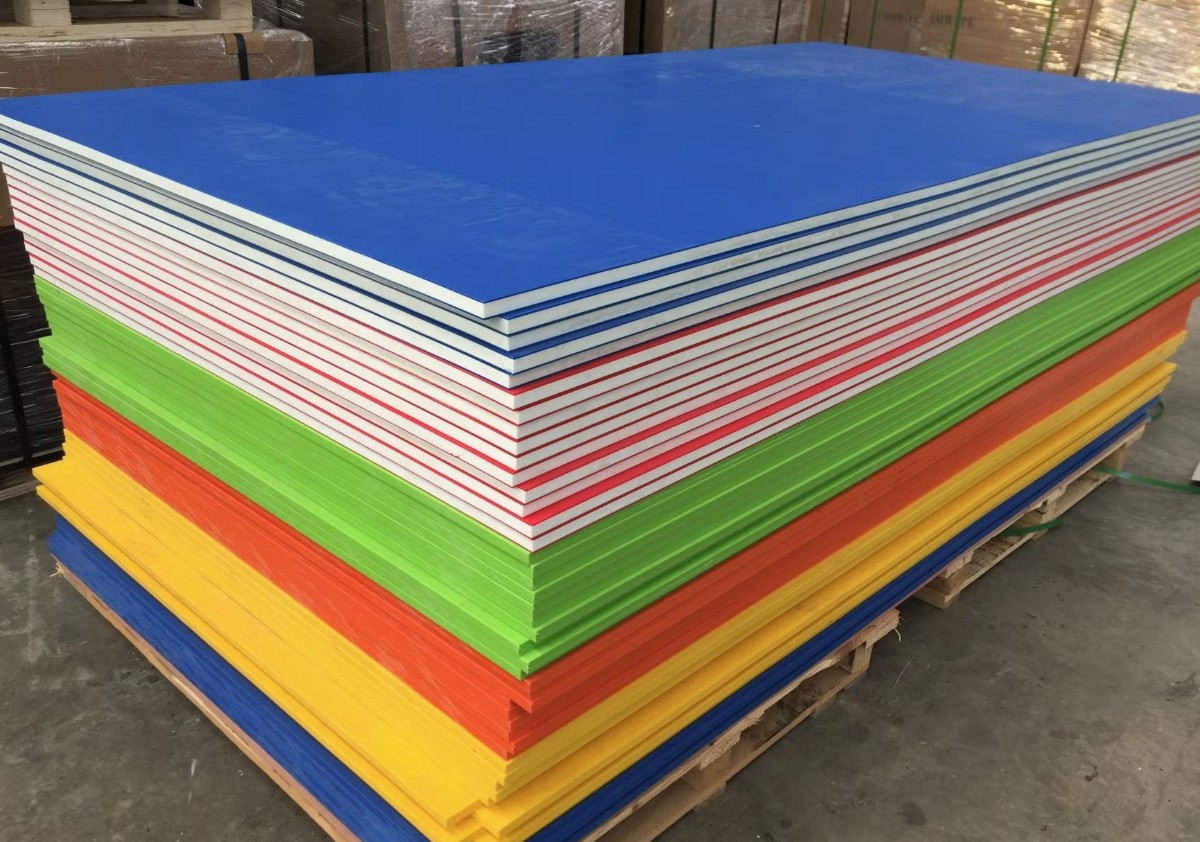 Plastic Sheets Cut to Size: Essential Considerations for Your Projects A stack of colorful plastic sheets in various sizes and colors including blue, white, red, green, orange, and yellow, are neatly stacked on a wooden pallet.