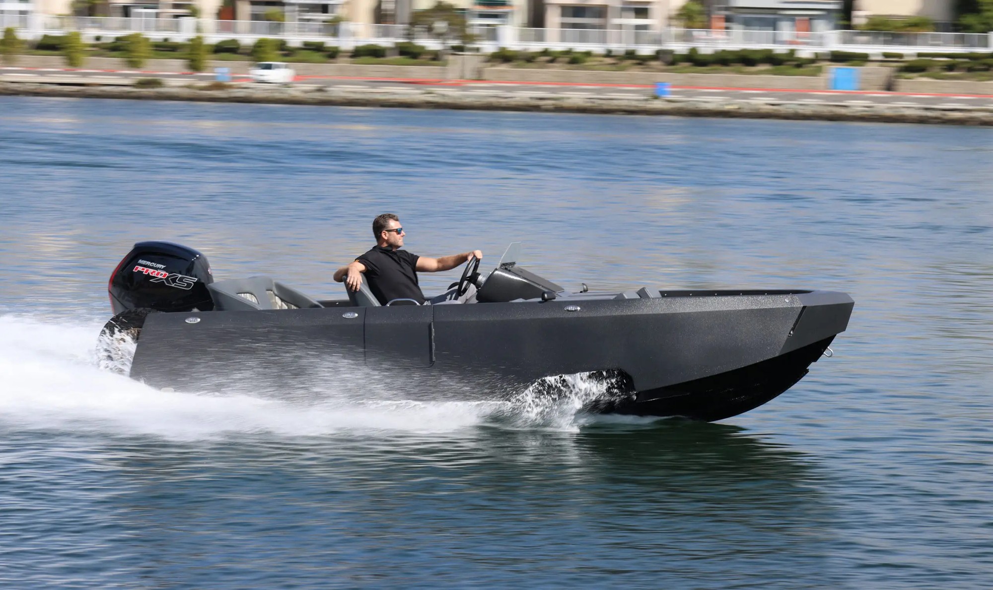 A man driving a WaterCar amphibious vehicle at speed on the water, demonstrating its boat mode.