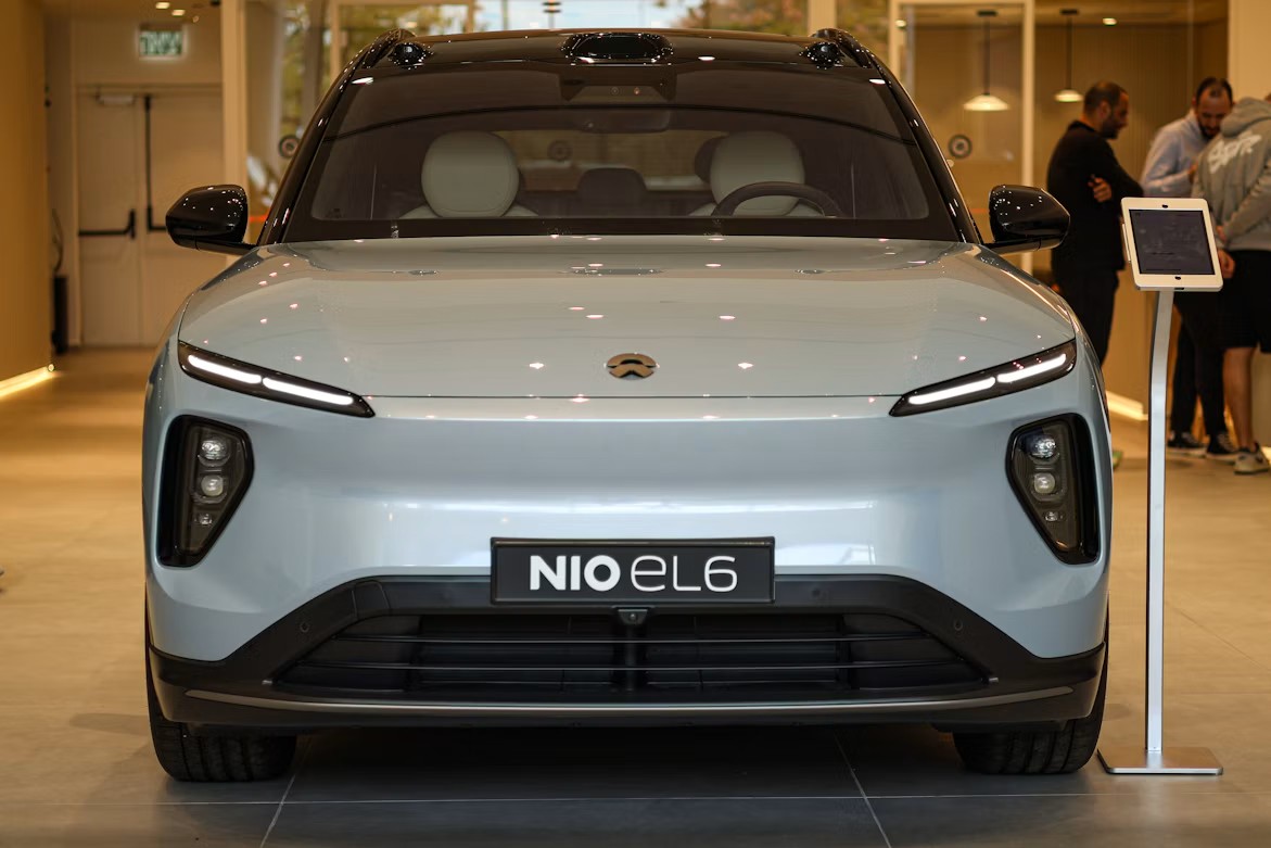 Automotive Engineering Shifts Toward Eco-Conscious Innovations in Luxury Transport Front view of a light blue Nio EL6 electric SUV parked indoors with a display tablet nearby.