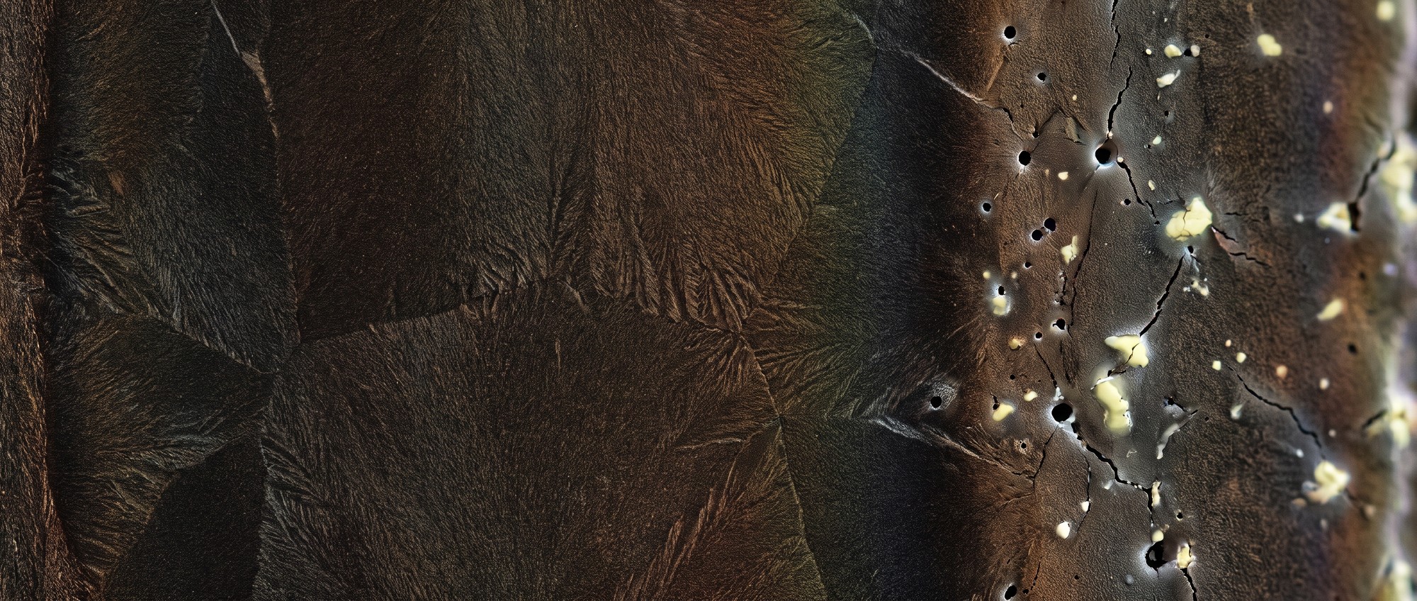 Macro photograph of a perovskite thin film surface showing smooth crystalline grains beside a patch of pinhole defects