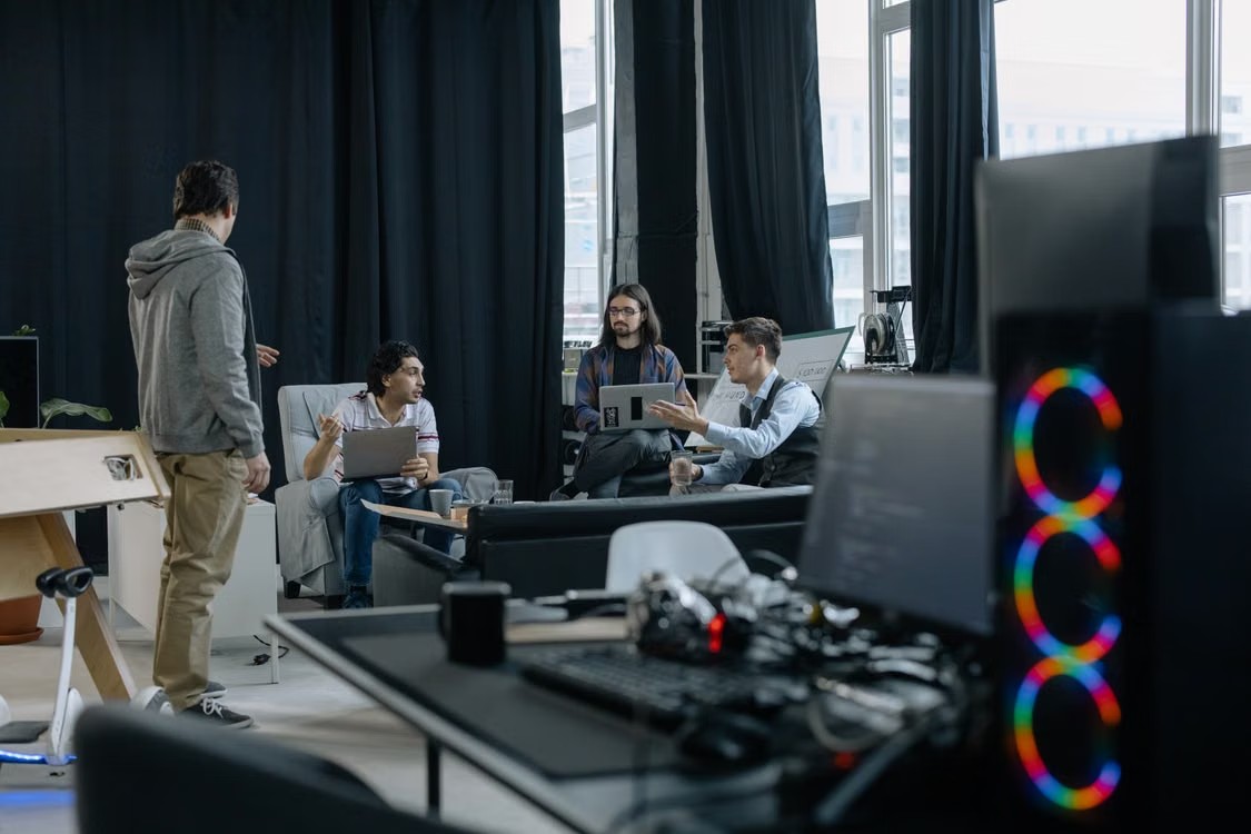 A group of technology professionals collaborating in a modern office with computers.